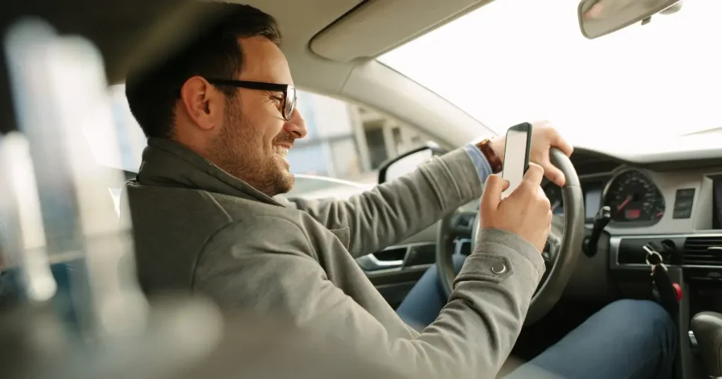 Current image: man looking at phone while driving