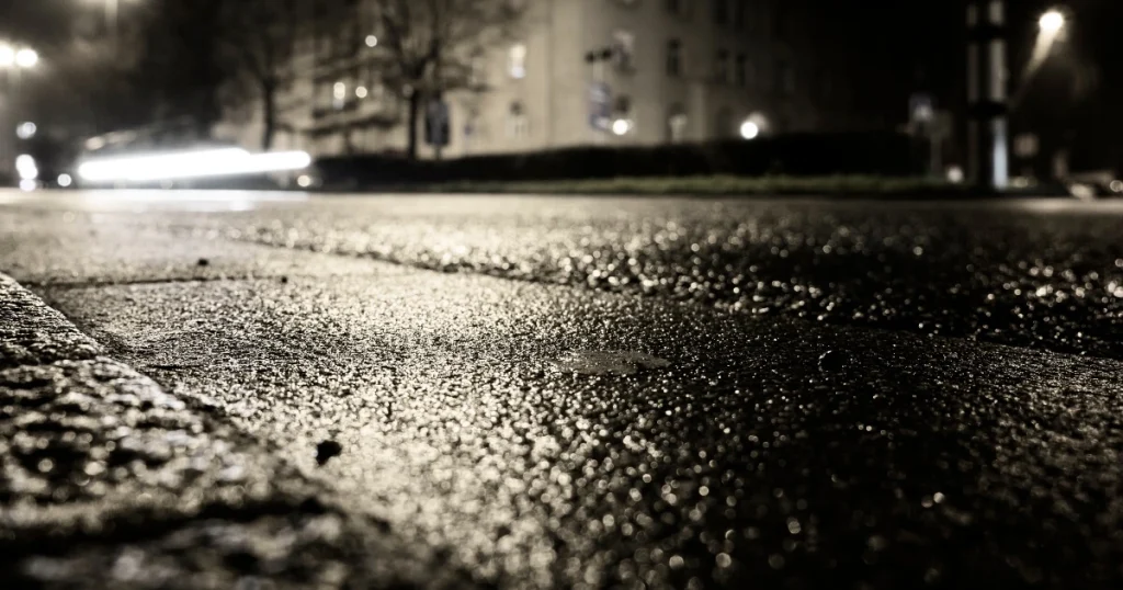 Current image: low ground-level image of black ice on local road at night|low ground-level image of black ice on local road at night