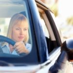 Current image: A woman checking rear view mirror
